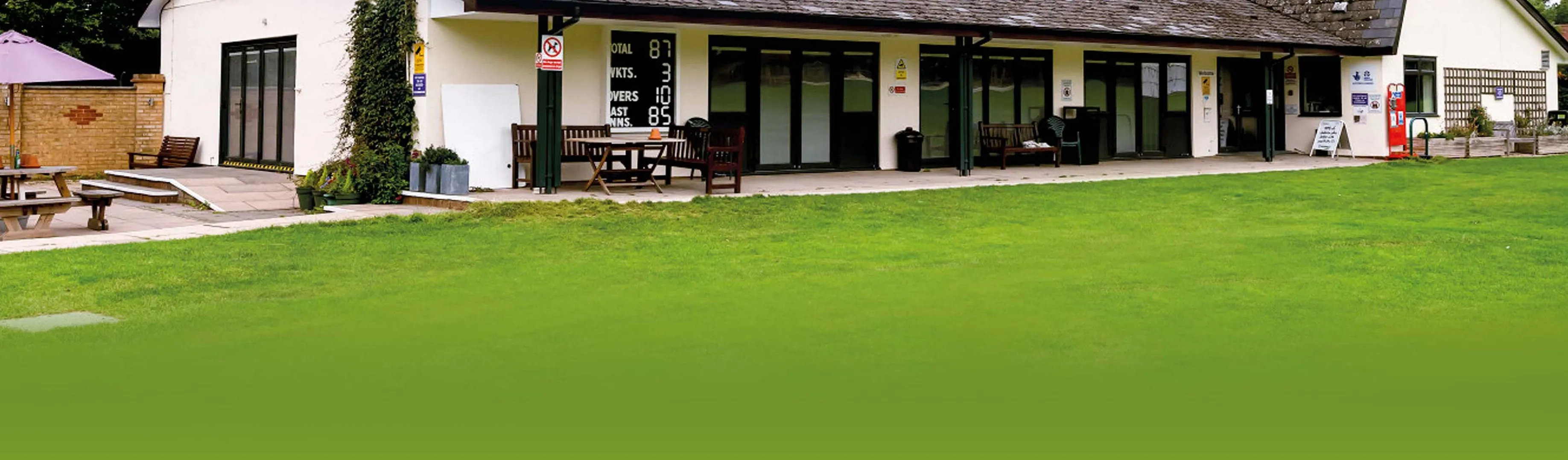 The Wandgas clubhouse, a long white pavilion with its cricket scoreboard, overlooking the field