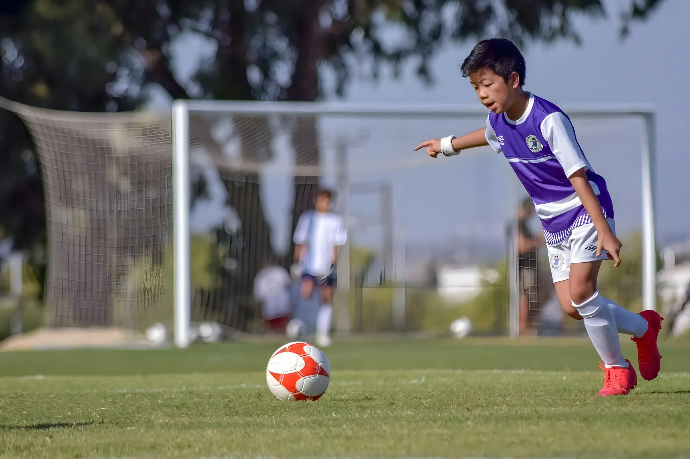 A young footballer in purple running with the ball